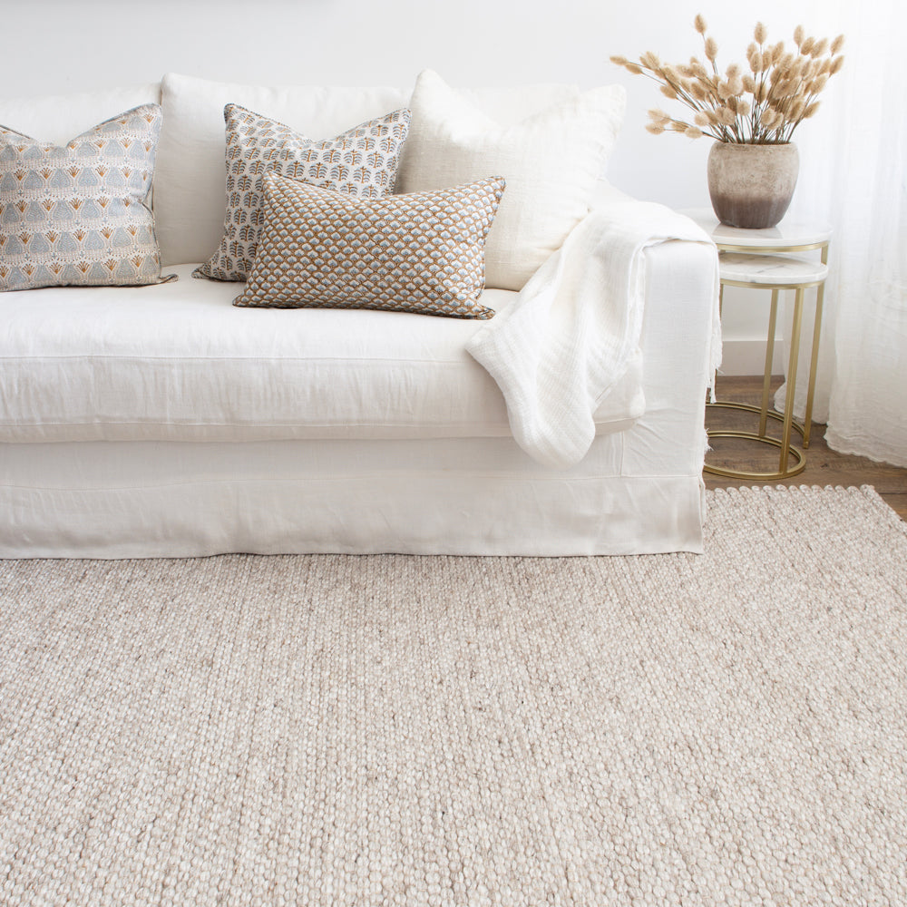 Warm, light coloured indoor outdoor rug styled with white sofa.