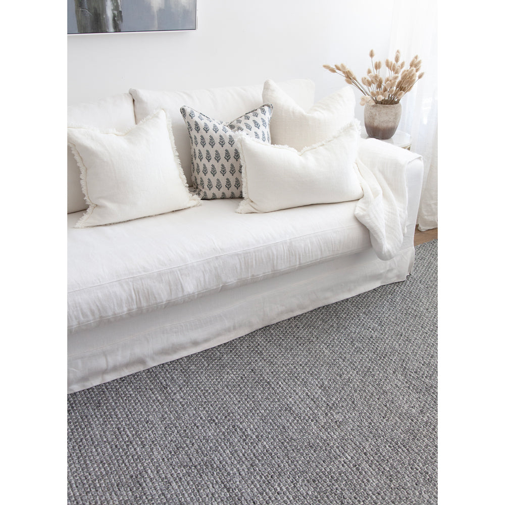 Charcoal grey rug with white sofa.