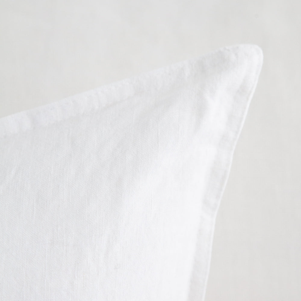 Close up of square white linen cushion.