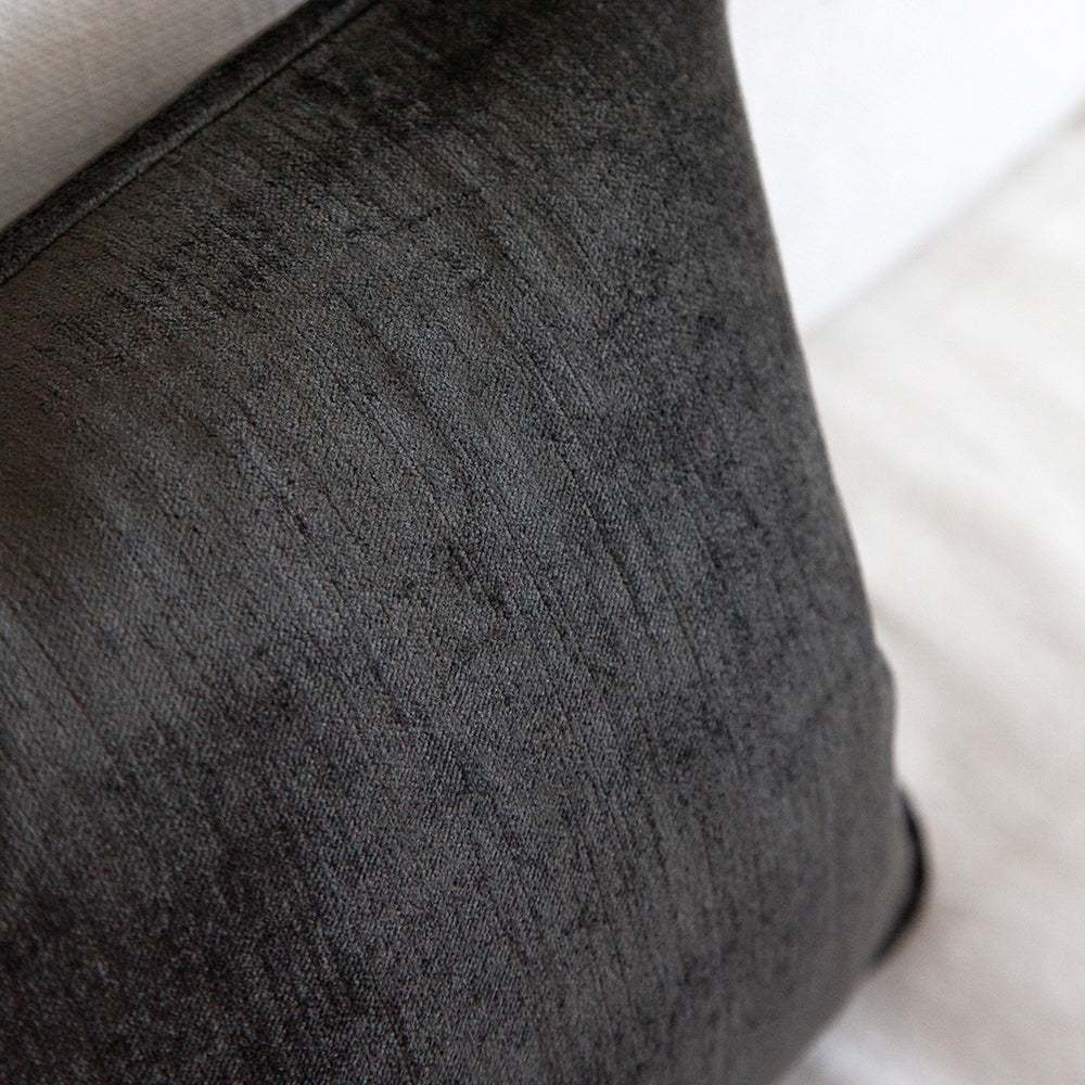 Small black velvet cushion on white sofa.
