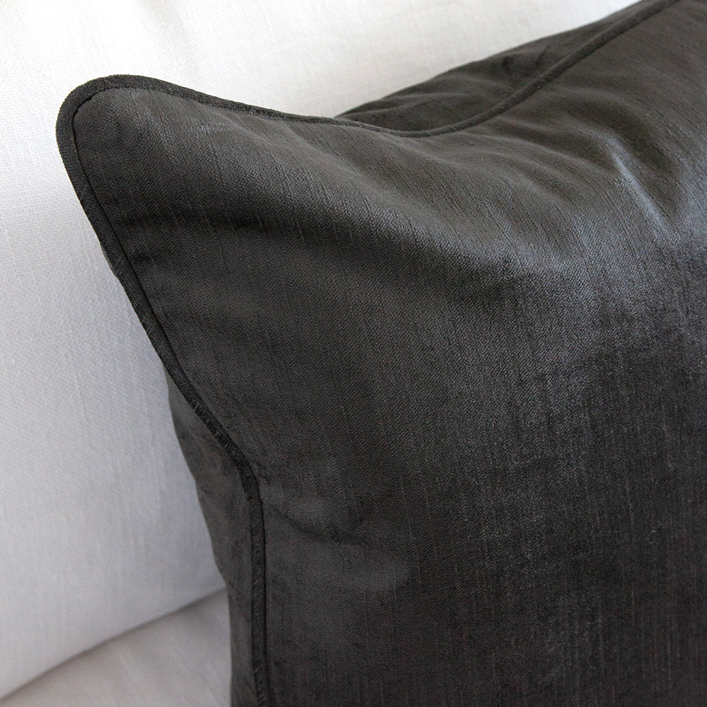 Close up of graphite velvet cushion on white sofa.