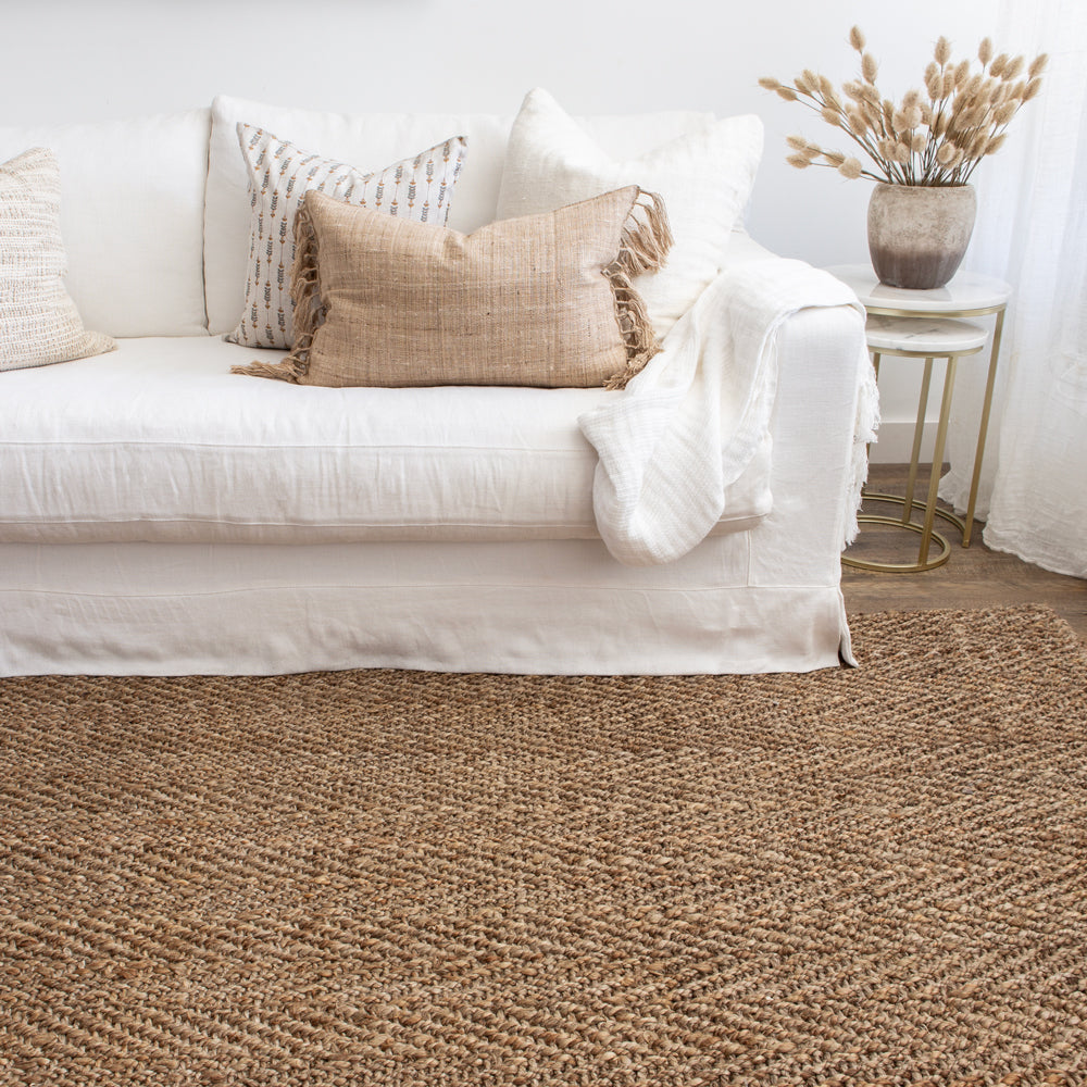 Jute floor rug with herringbone weave featured wit white sofa.