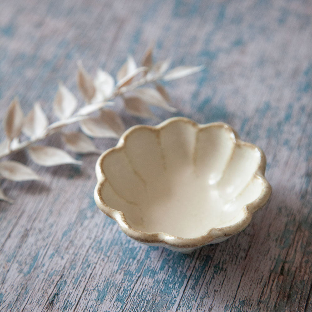 Rinka sauce dish. Small bowl with scalloped edged design resembling a flower. The dish is has three small feet. 