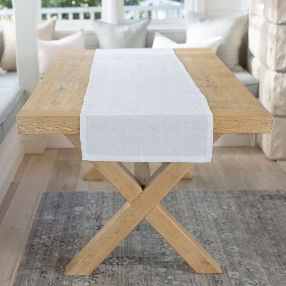 White linen table runner on wooden table. 