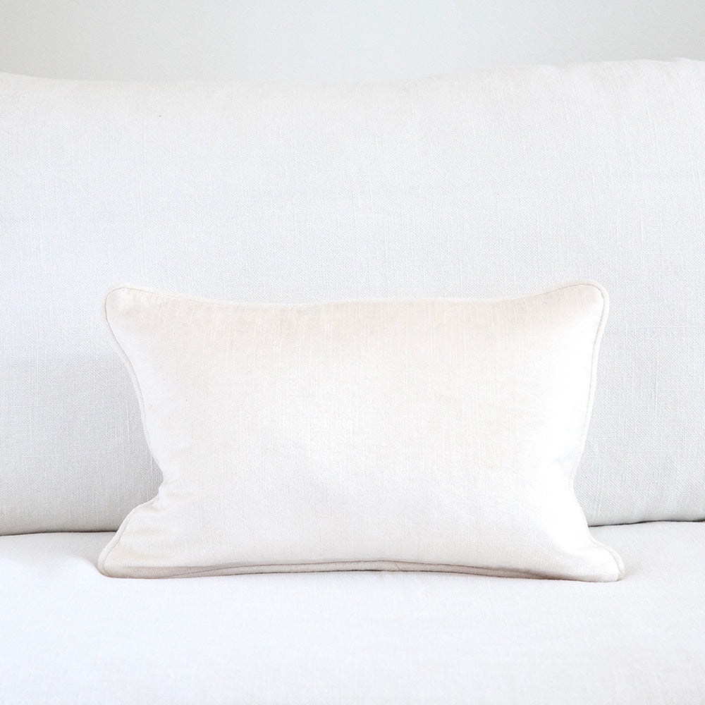 Small Ivory coloured velvet cushion on white sofa.