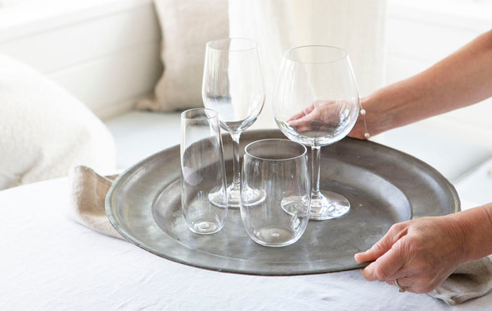 Glassware on a silver serving tray, held by Tara.