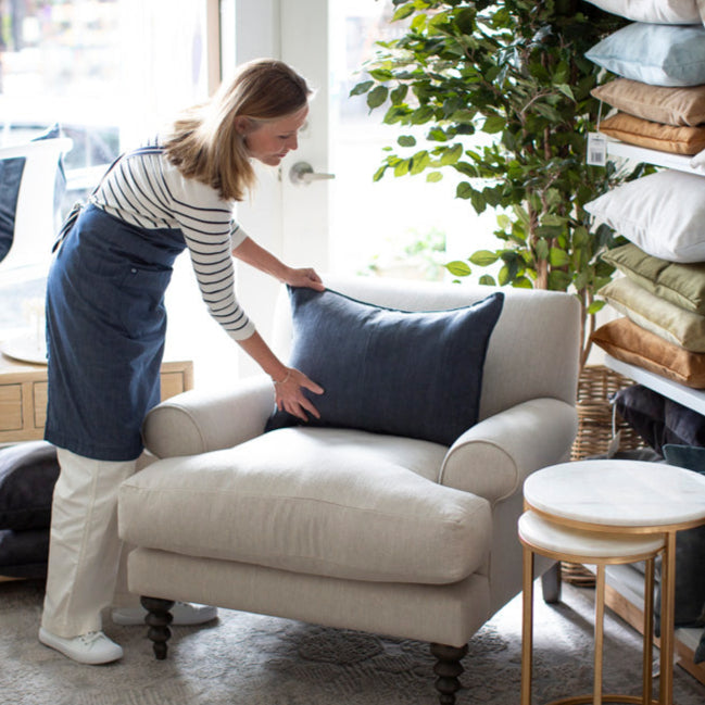 Tara Dennis placing a cushion  on an armchair. Molmic Coogee Sofa Armchair
