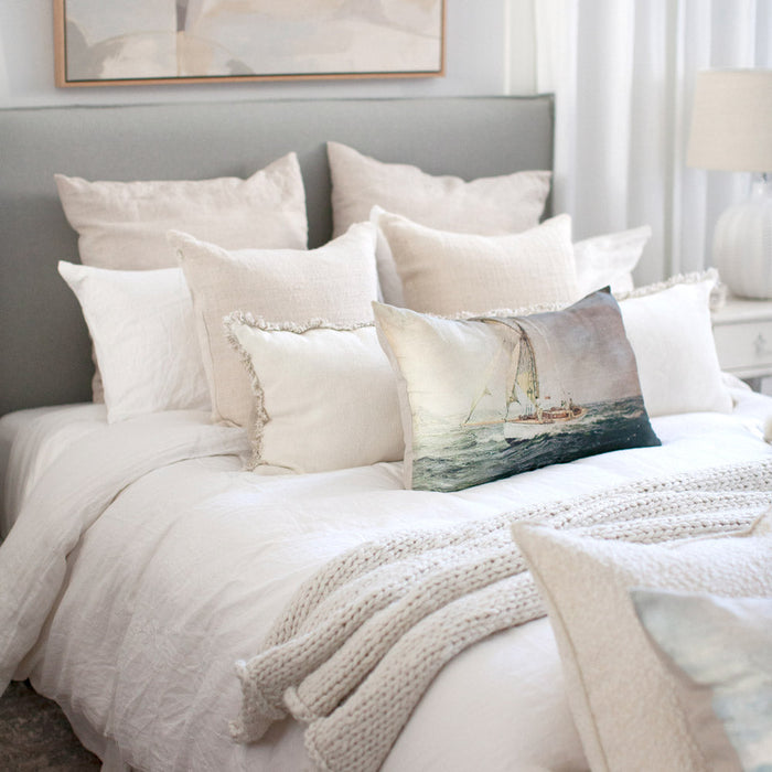 A throw on a bed, with cushions and a dog 