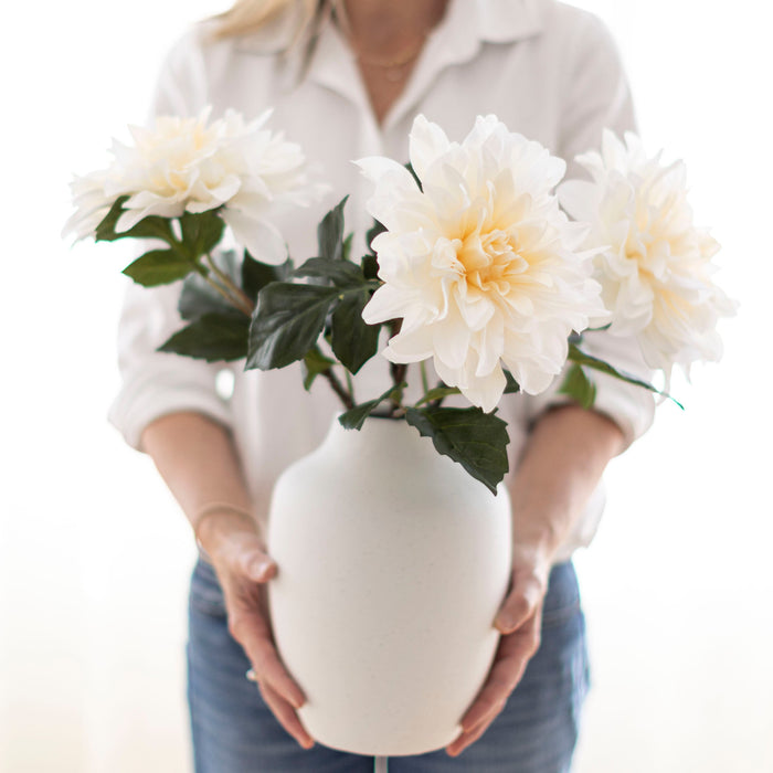 Tara holding a vase of faux daliah flower stems.
