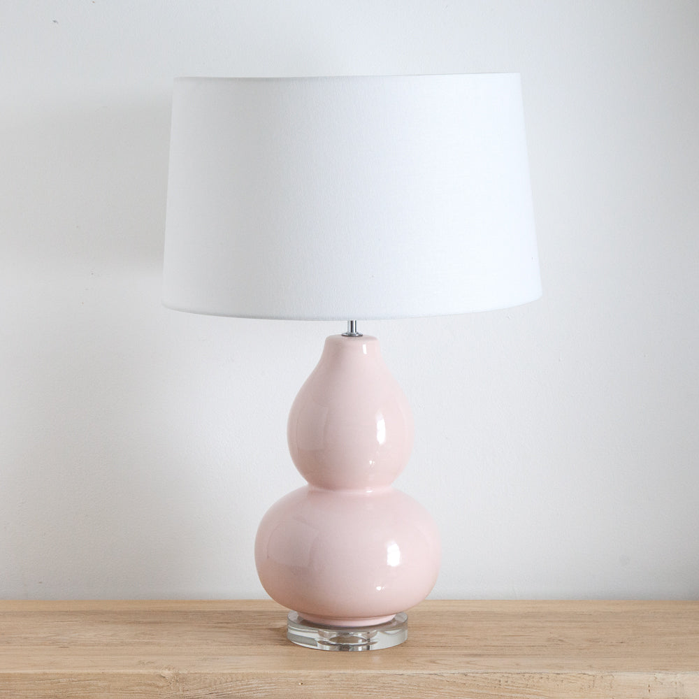 Table lamp with pink high gloss ceramic base with white linen shade.