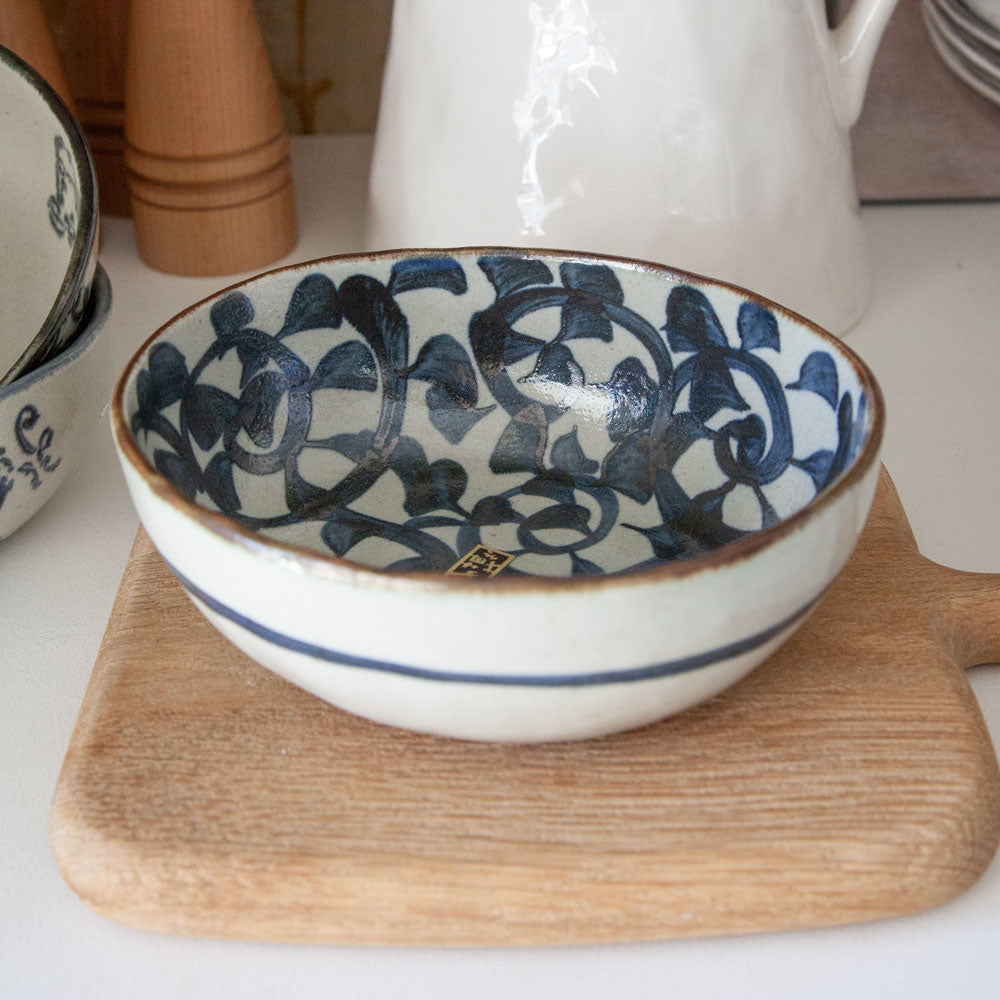 Oval ceramic bowl with hand painted vine design on the inside surface and blue stripe around the outside.