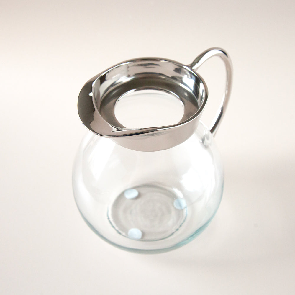 Clear glass jug with metal spout and handle.
