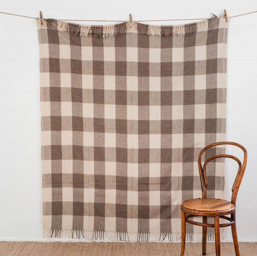 The Grampian Goods Co Brown tartan recycled wool blanket displayed on a wall to show the full pattern of the tartan.