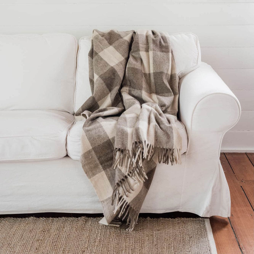 The Grampian Goods Co Brown tartan recycled wool blanket on white sofa.