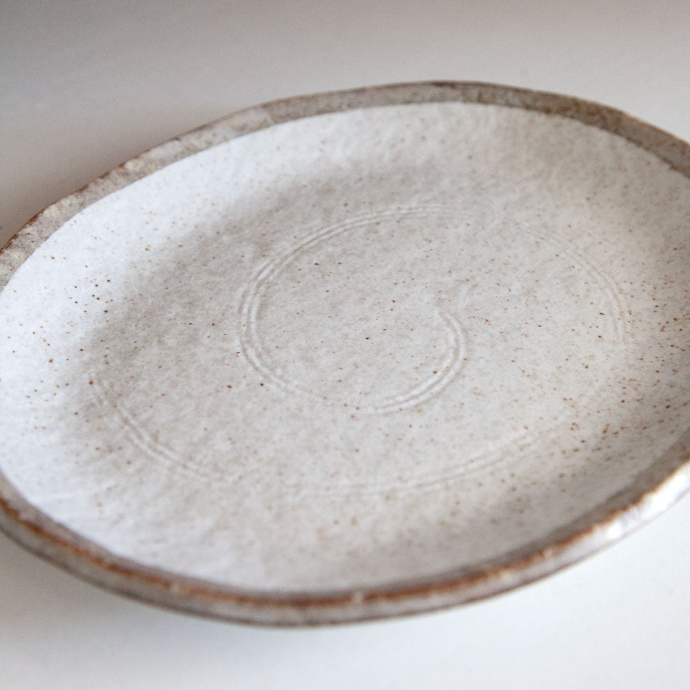 Close up of swirl design on Shirokaratsu ceramic plate with brown rim.