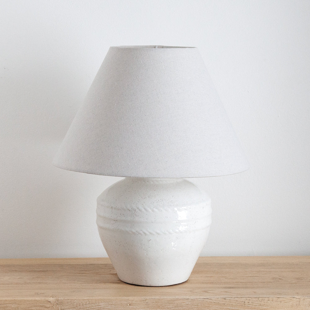 Rustic white ceramic lamp with tapered linen shade.