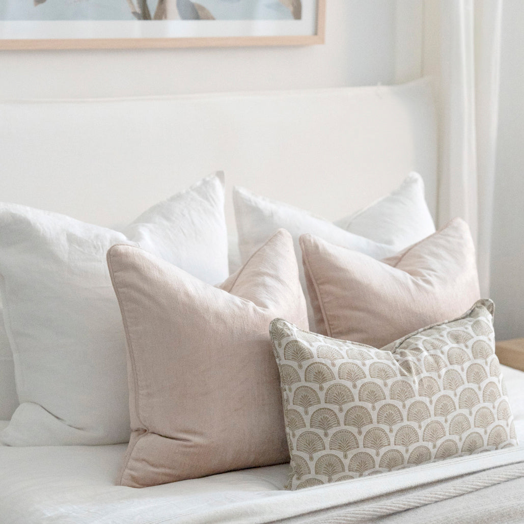 Soft pink velvet cushions styled on bed with white bedding.