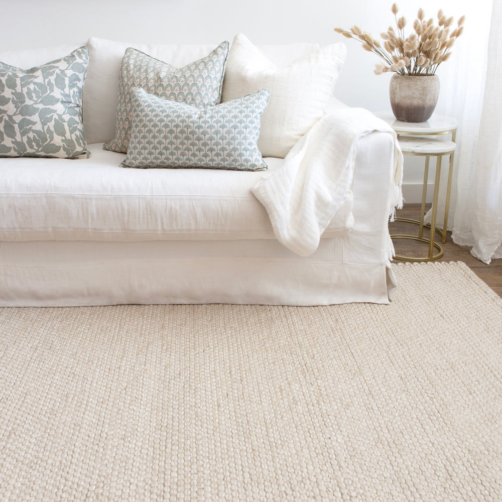 Light coloured indoor outdoor rug with white sofa.