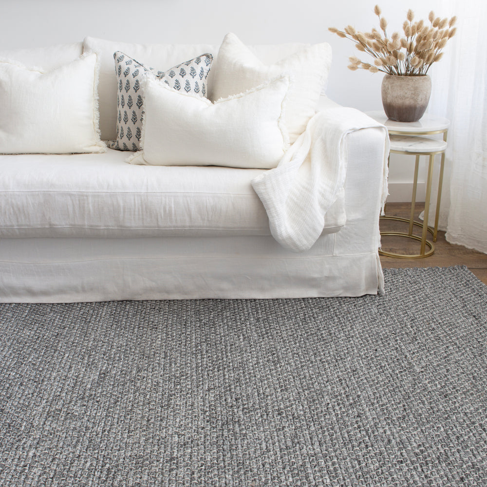 Charcoal grey indoor outdoor rug with white sofa.
