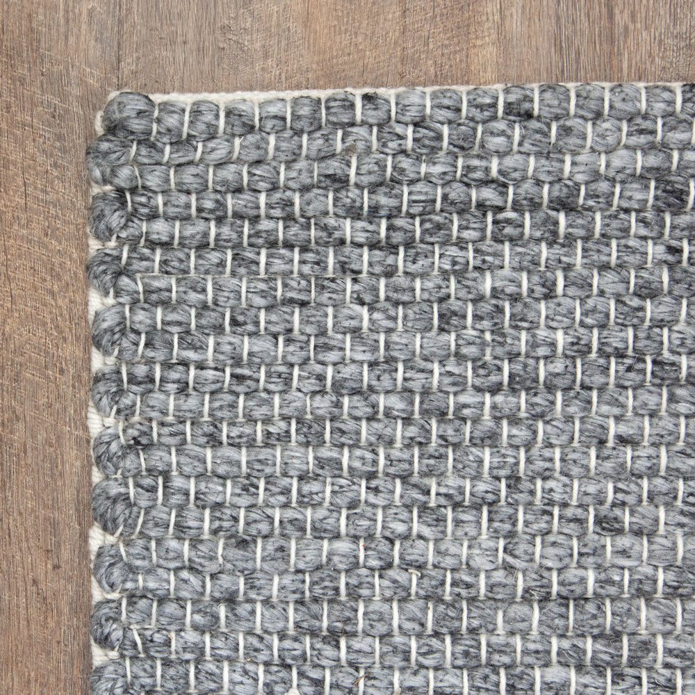 Close up corner photo of charcoal grey indoor outdoor rug.