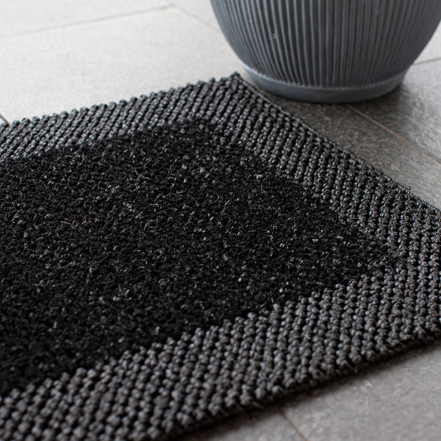 Black doormat with border detail. 