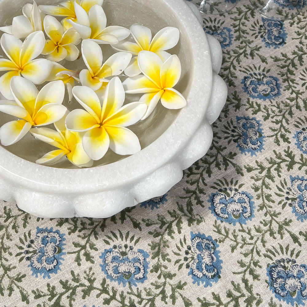 marble bowl with floating frangipanis on floral printed tablecloth. 