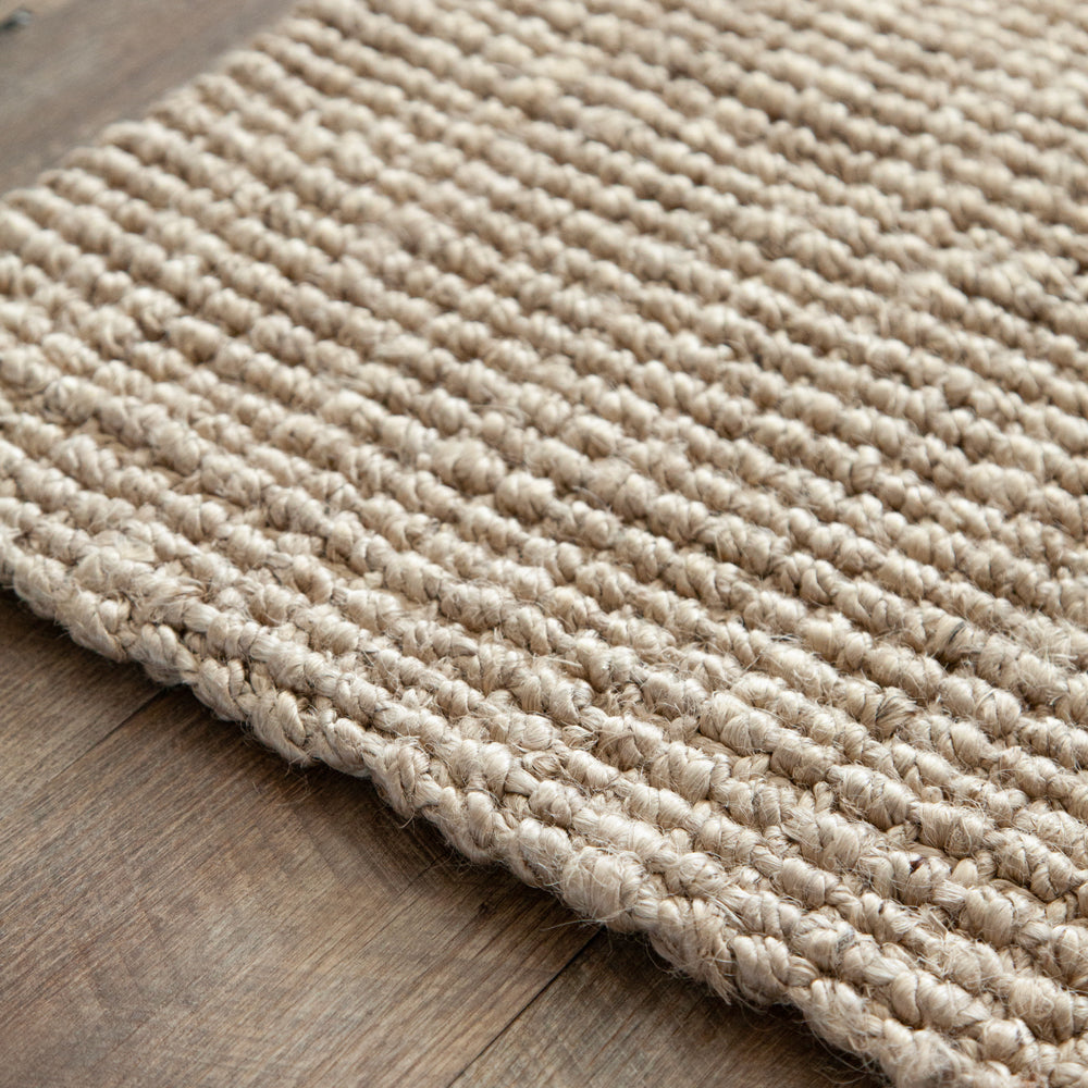 Close up of blond jute door mat on wooden floor.