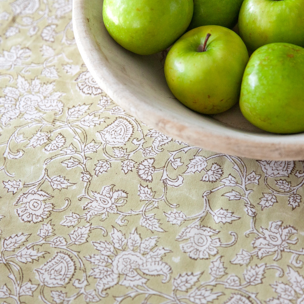 Green paisley block printed tablecloth with bowl of green apples. 