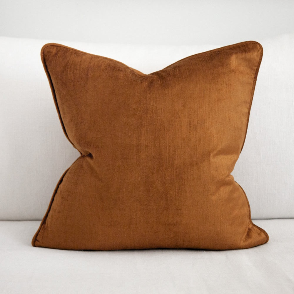 Ochre coloured square velvet cushion with piping. 