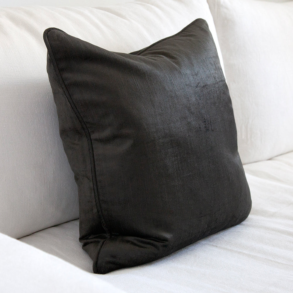 Graphite velvet cushion on white sofa.