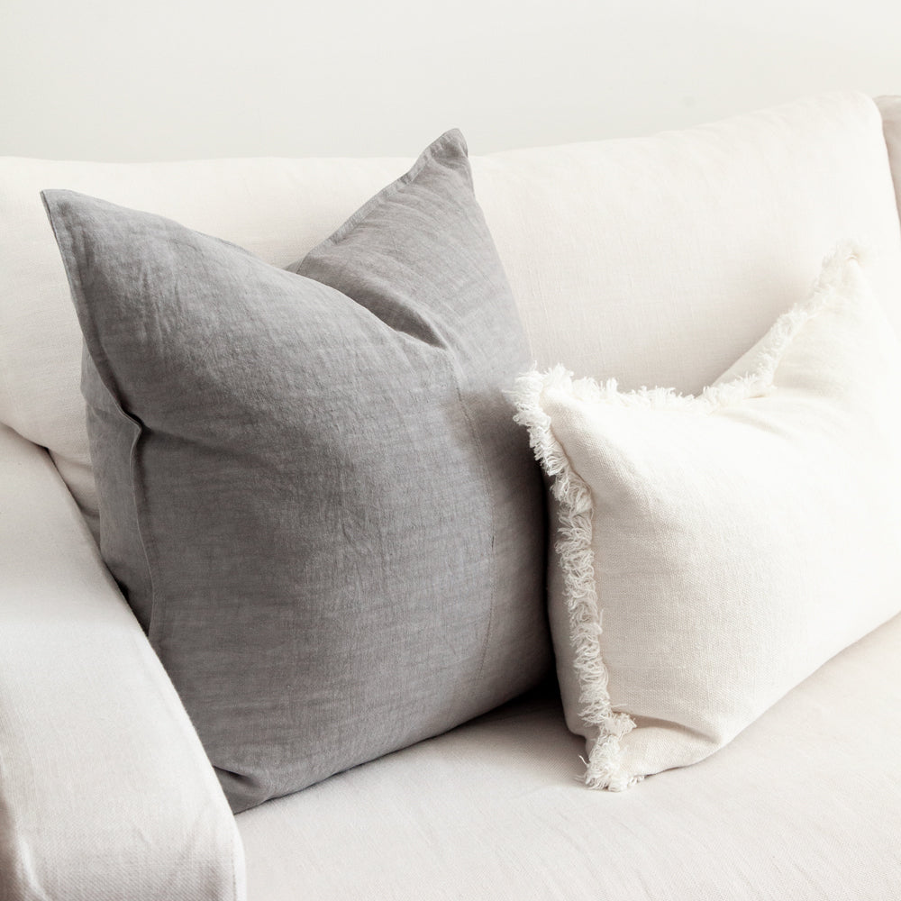 Large square grey linen cushion with white fringed rectangular cushion.