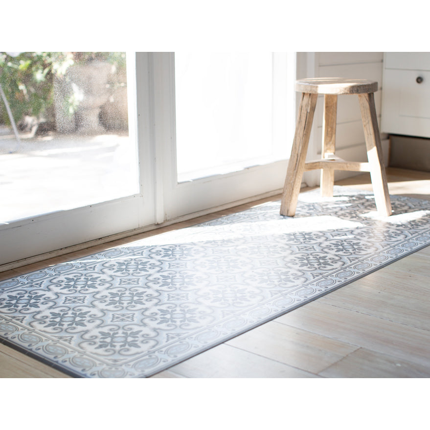 Blue and grey vinyl floor mat in front of door. Spanish tile design.