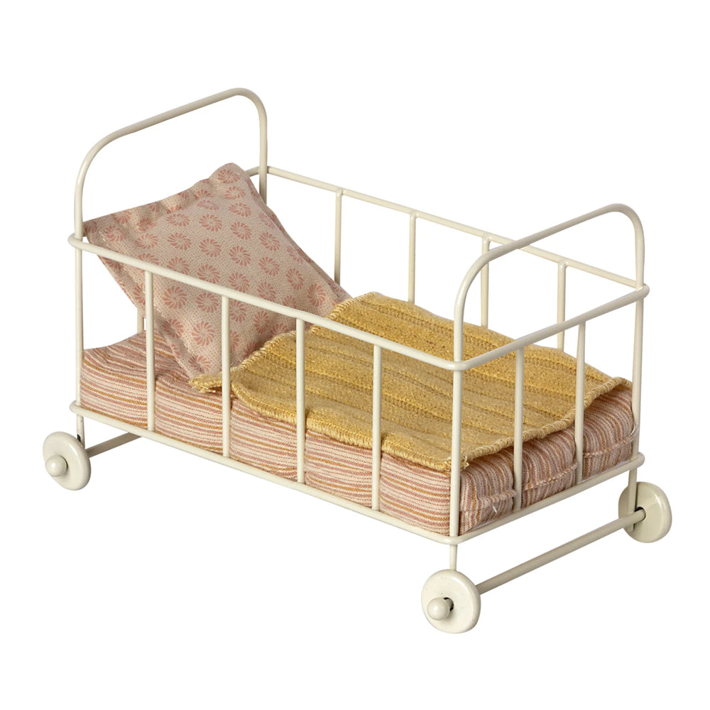 Maileg white cot with rose coloured bedding and yellow blanket.