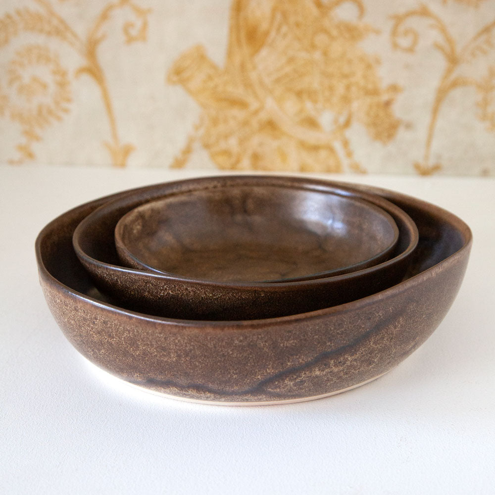 Three sizes of Mervyn Gers brown bowls sitting inside each other.