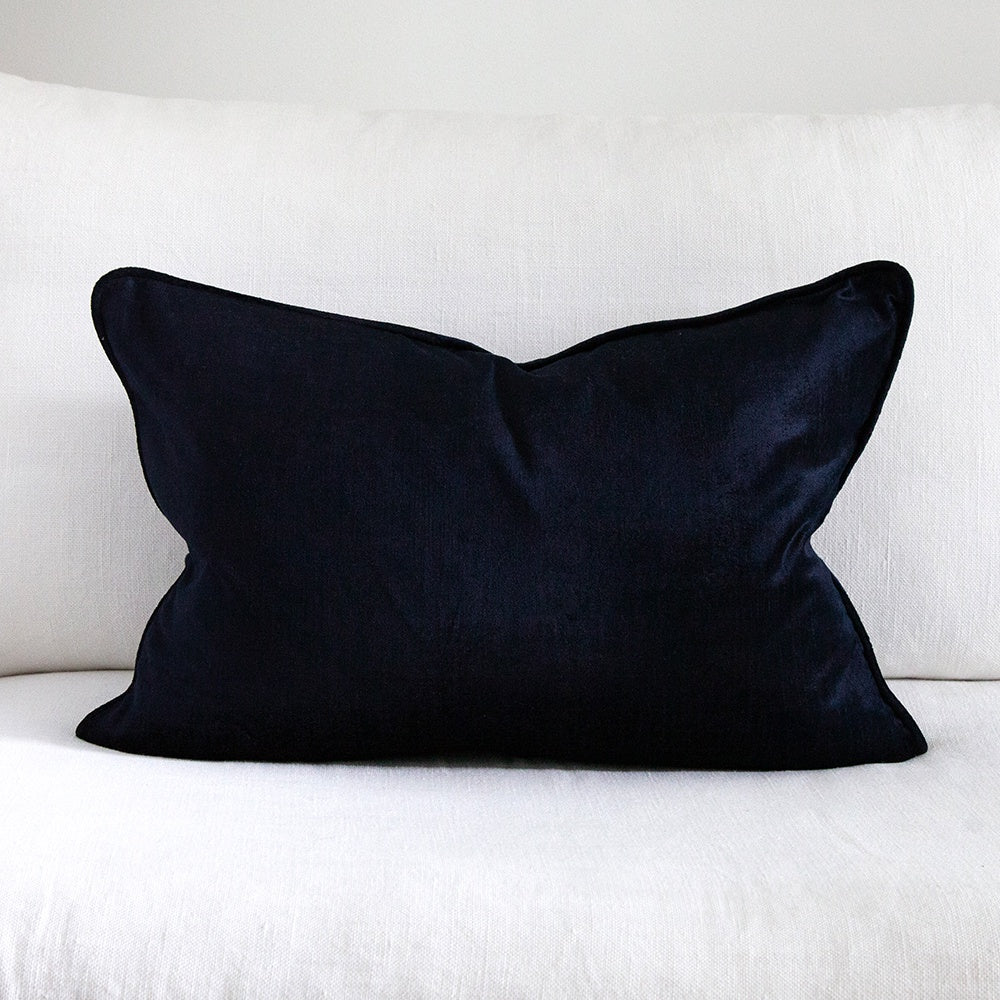 Dark blue velvet cushion on white sofa.