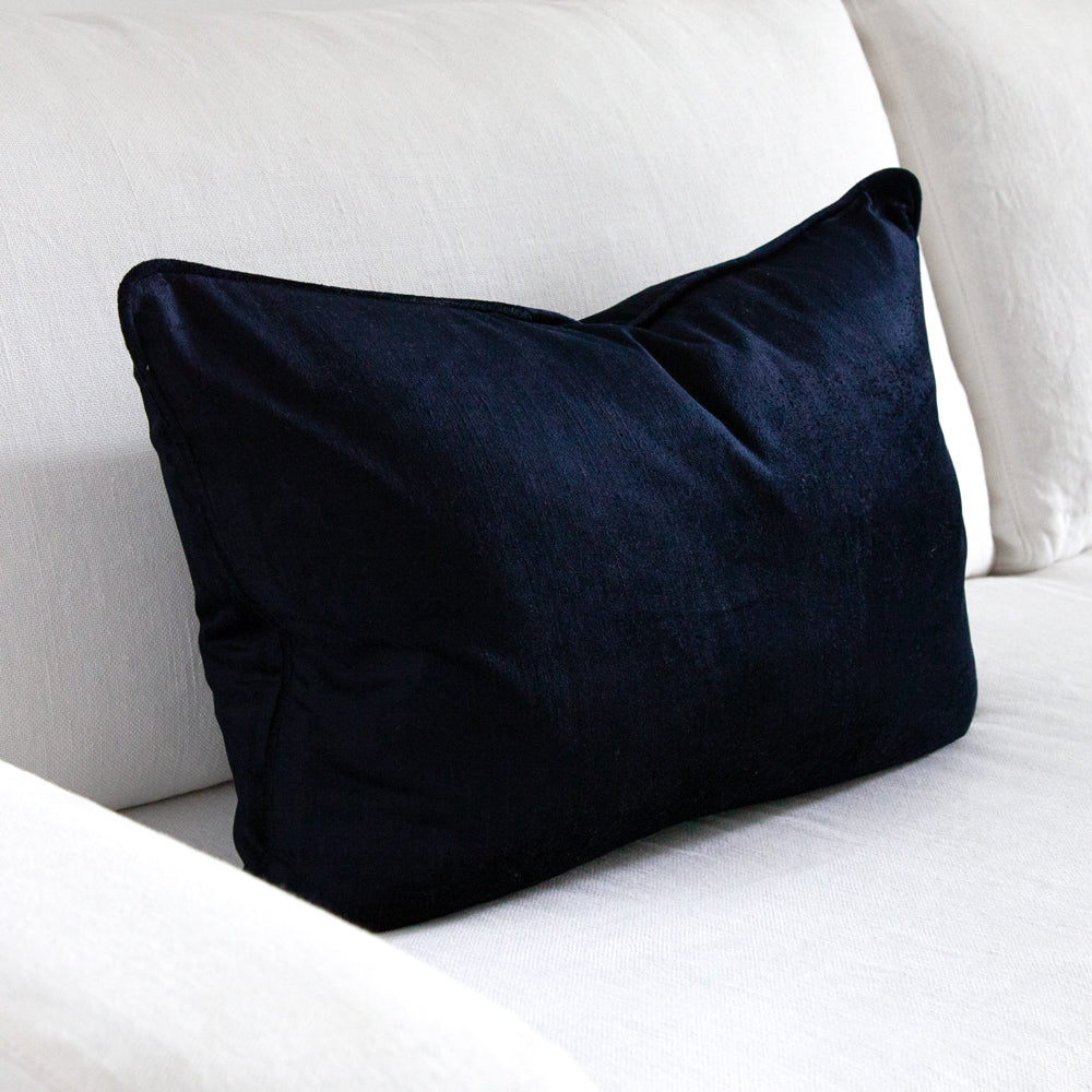 Dark blue velvet cushion on white sofa.