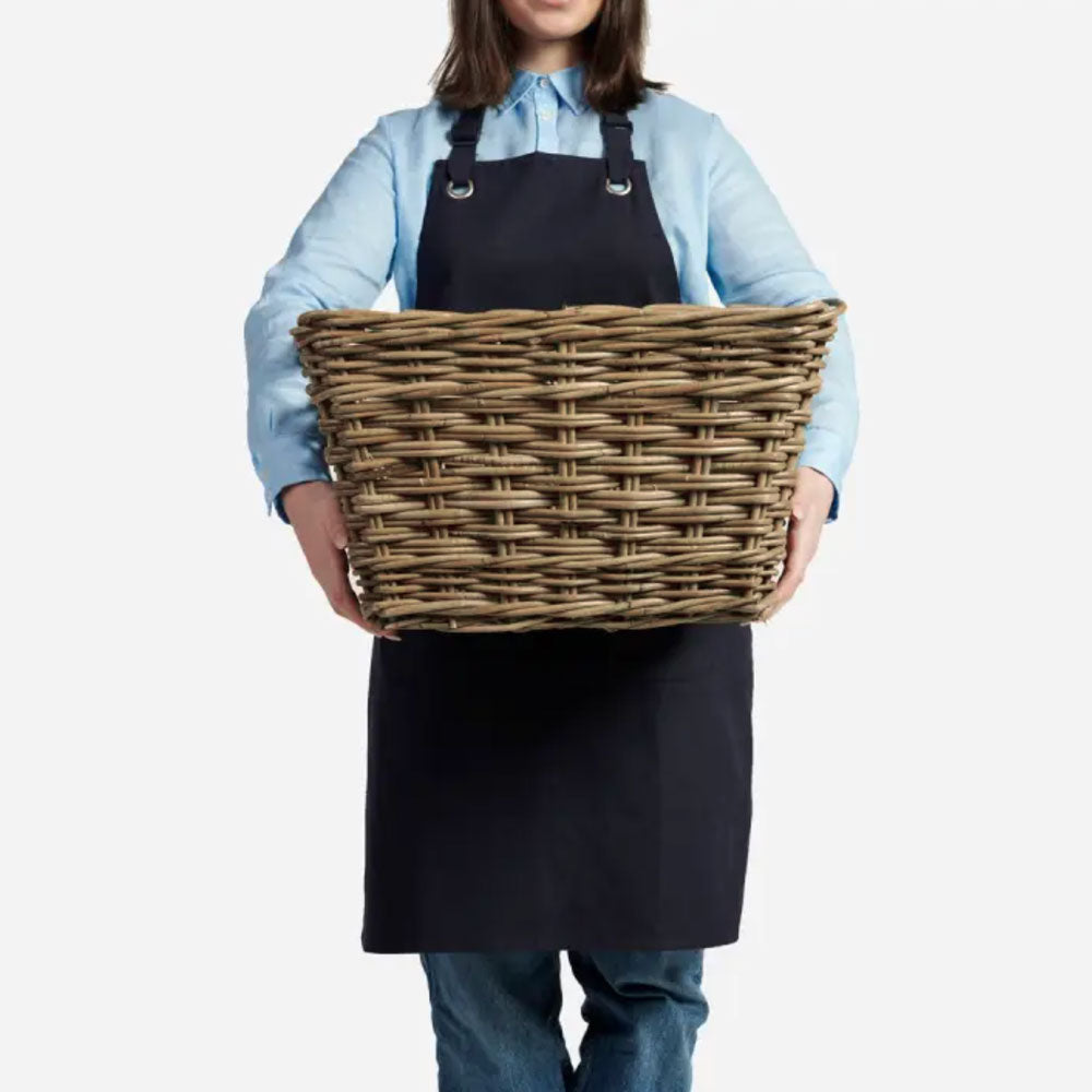 Woman holding rectangular rattan wicker storage basket.