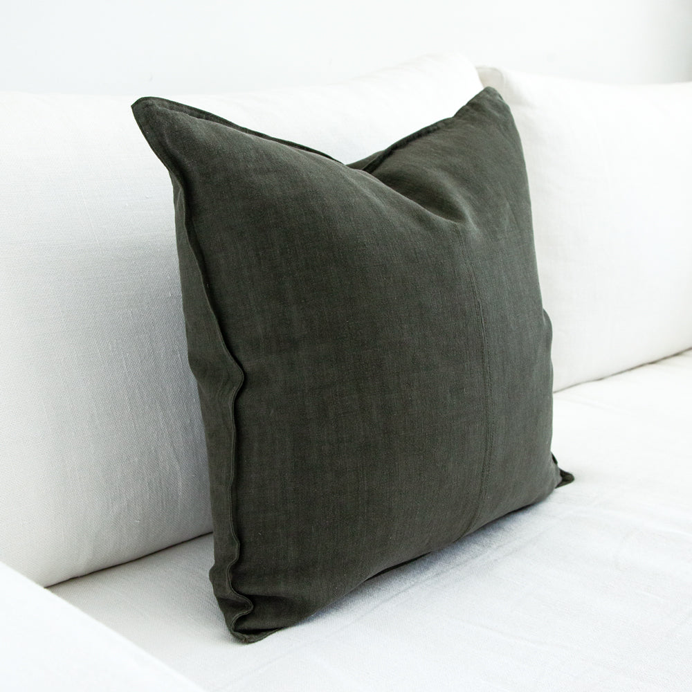 Dark green square cushion viewed from the side.