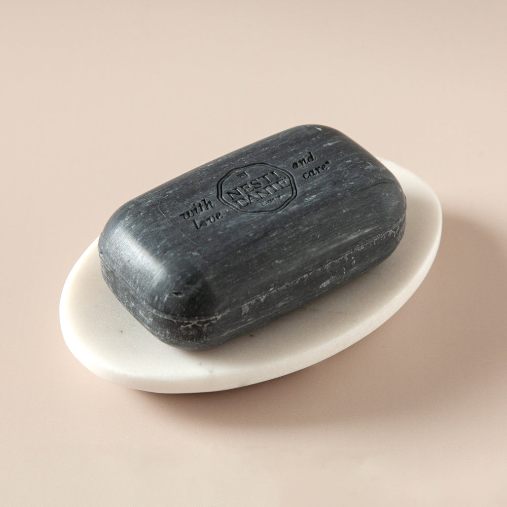 Oval marble soap dish with black soap.