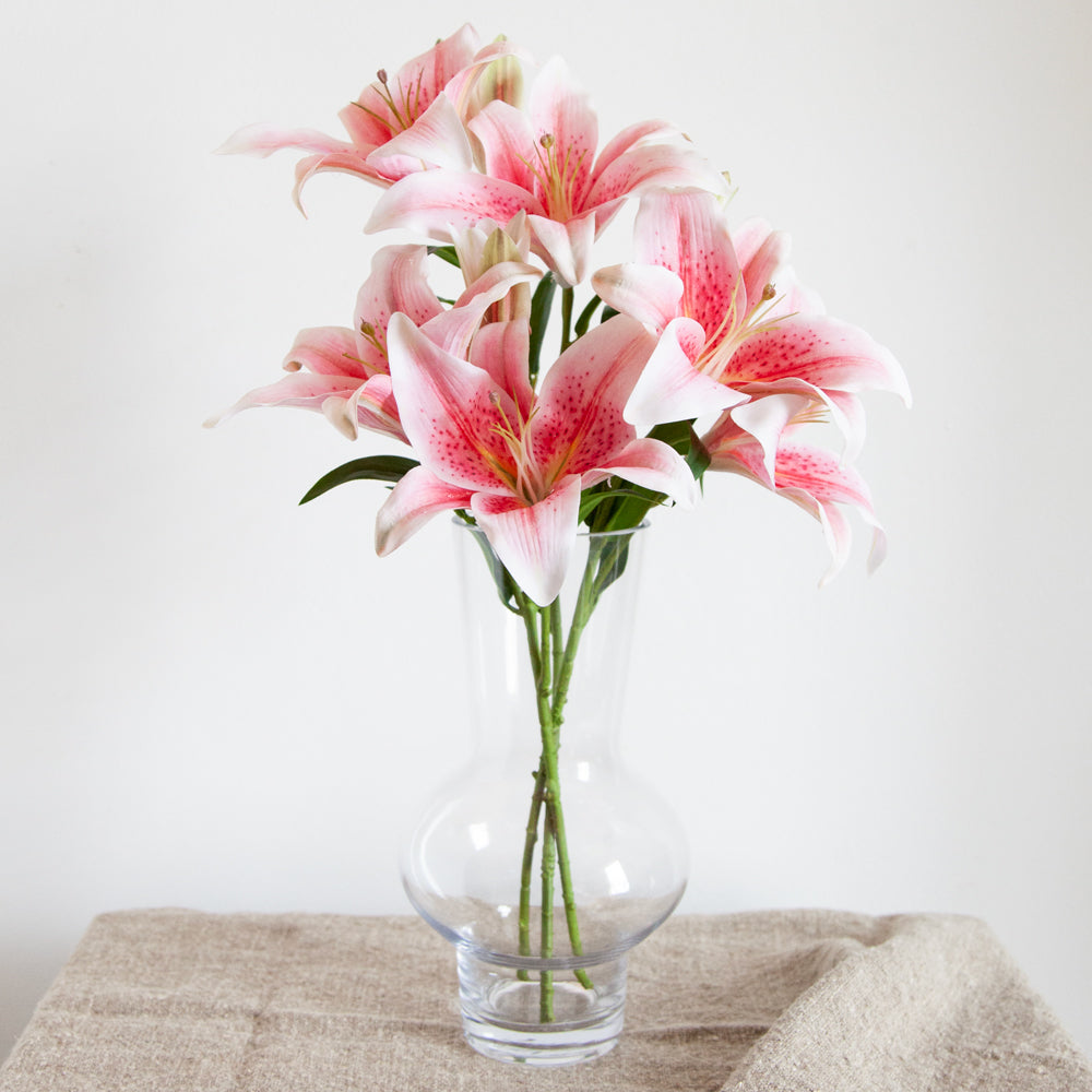 Artificial pink Lillies in a glass vase.