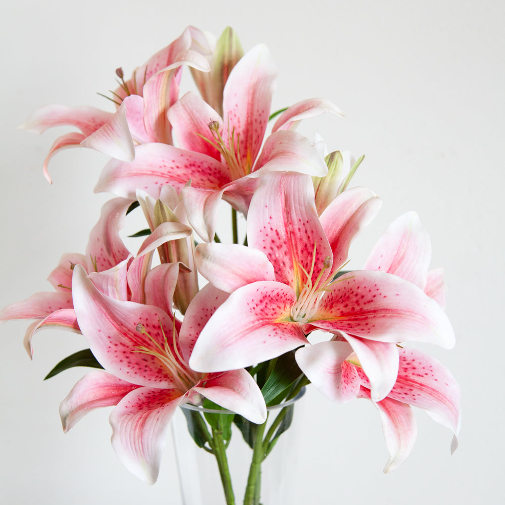 Artificial pink Lillies in a glass vase.
