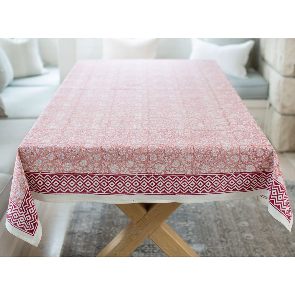 Red pink block printed tablecloth with floral motif and bold red boarder.