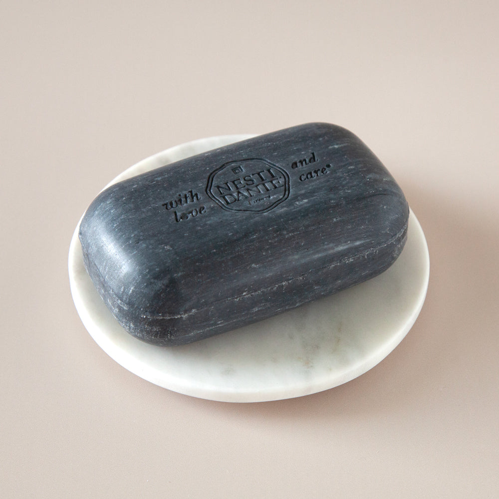 Round marble soap dish with black soap.
