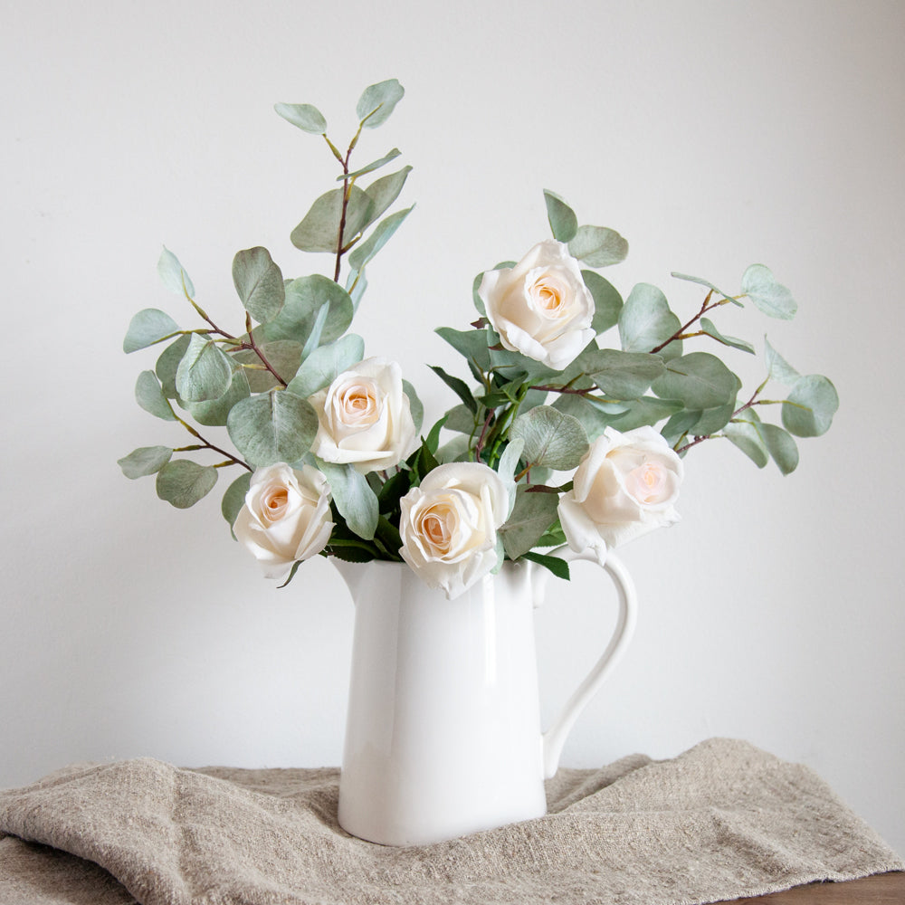 Artificial flower arrangement with roses and silver dollar eucalyptus. 