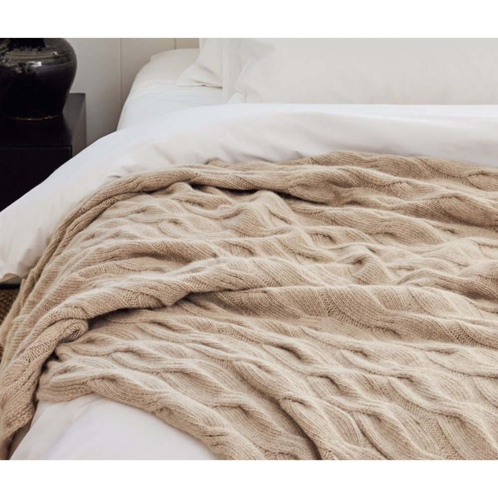 Bemboka angora merino chunky cable knit throw over the end of a bed.