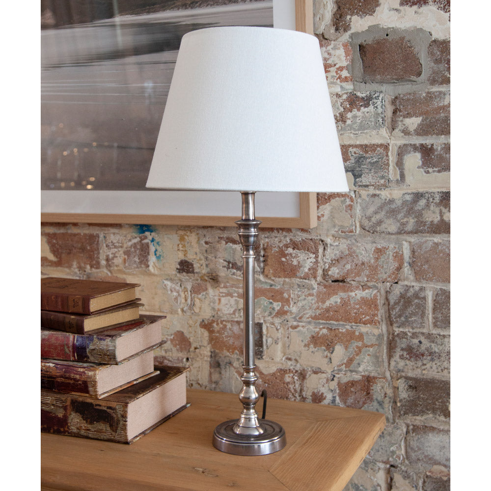 Table lamp with silver base and white shade.