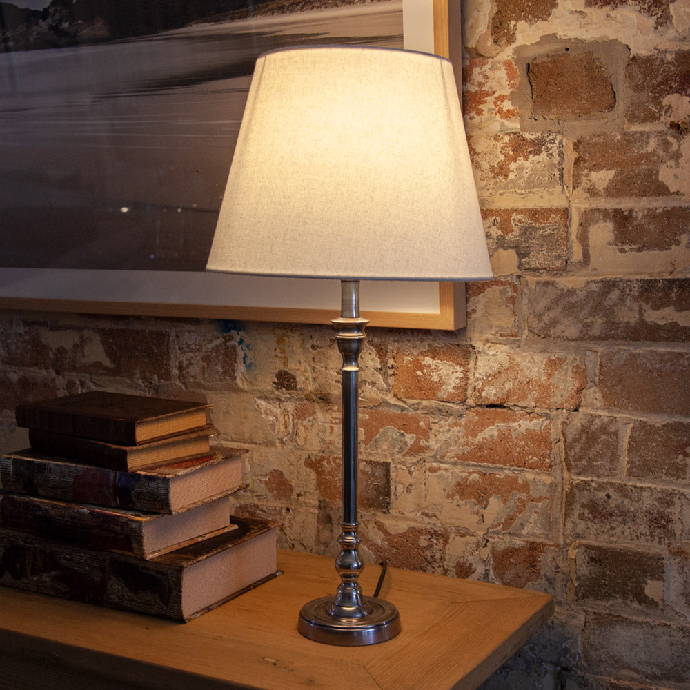 Table lamp with silver base and white shade.