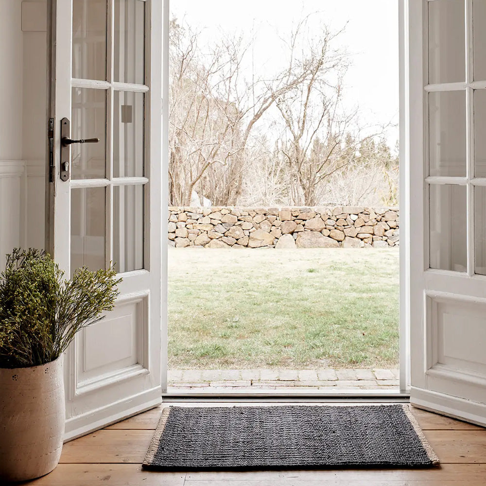 Armadillo charcoal nest entrance door mat sitting inside double french doors. 