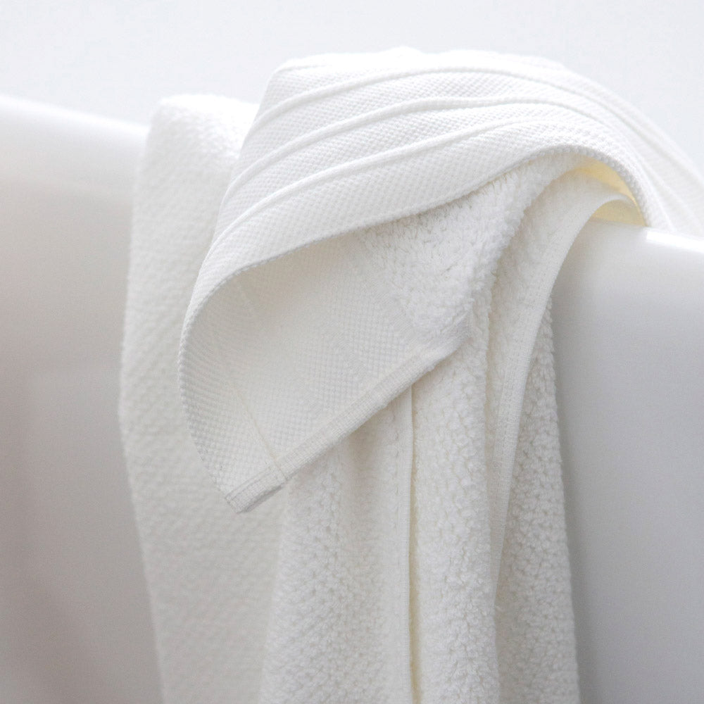 White Bemboka bath towel hanging over bath.