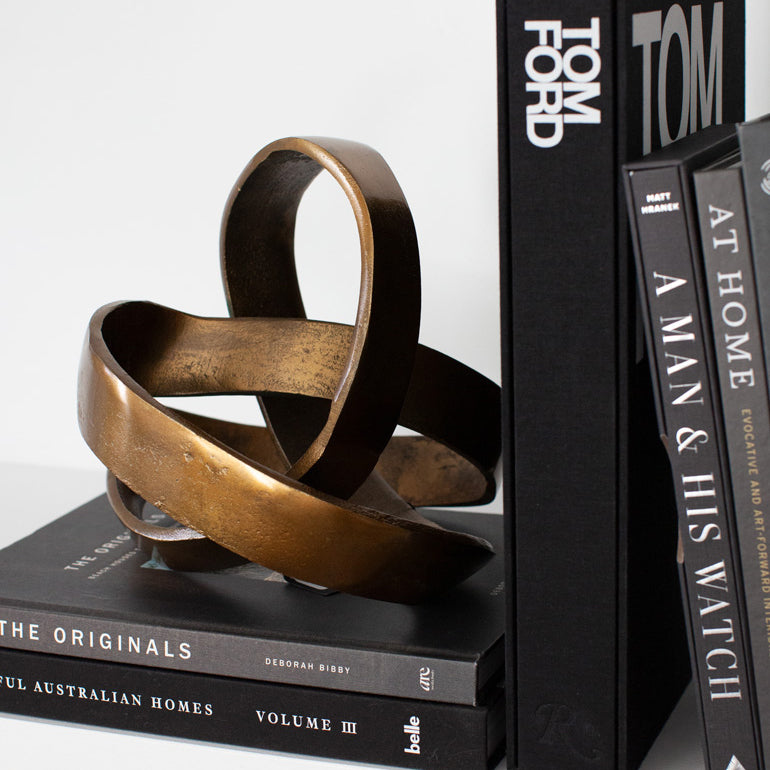 Freeform brass sculpture styled with black books.